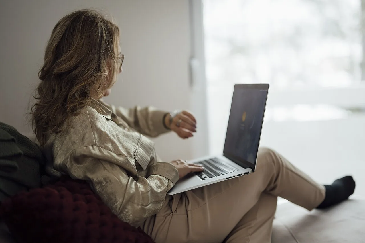 A woman checking the time while using a laptop