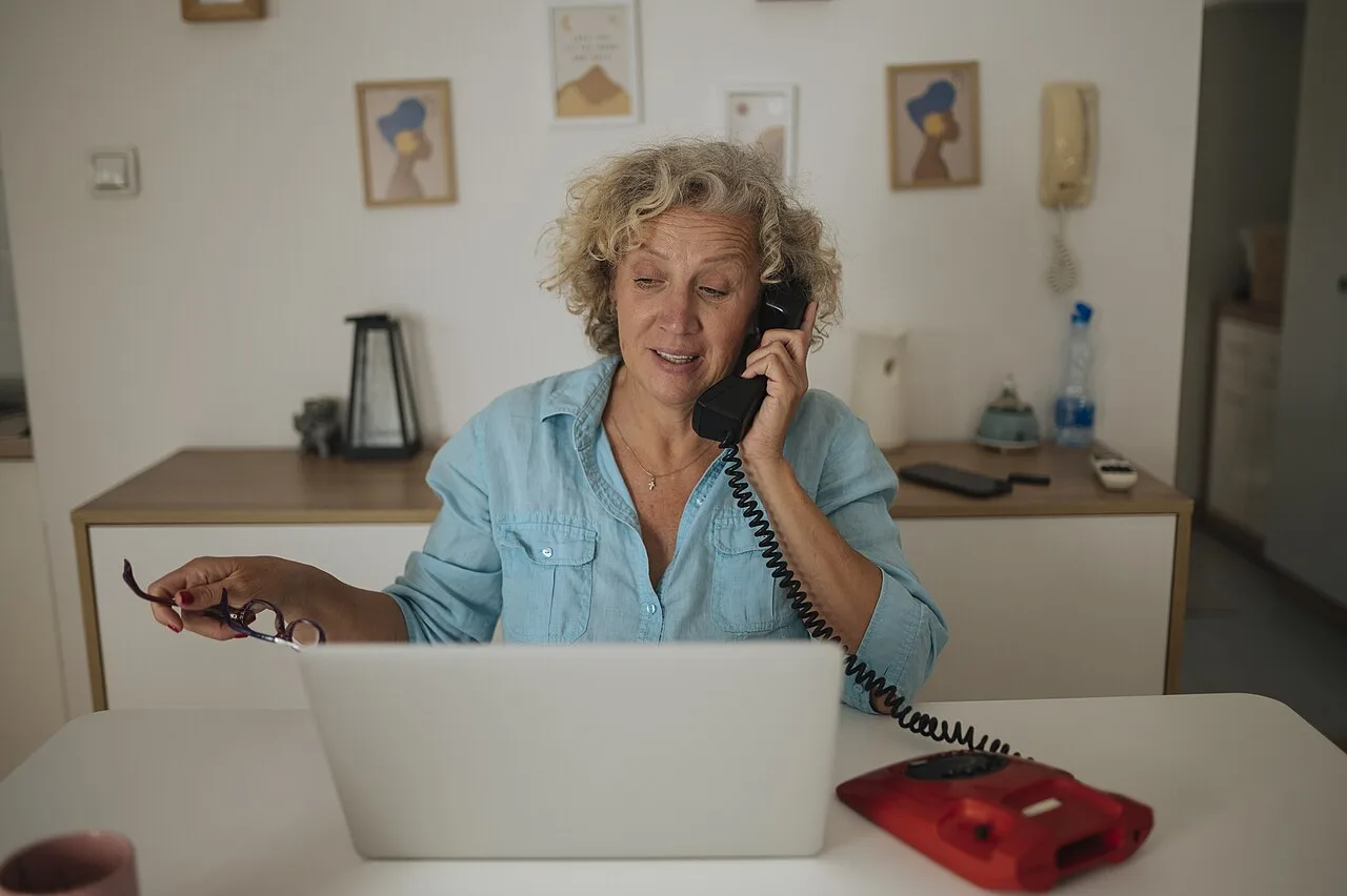 Adult woman using a laptop while speaking on a telephone